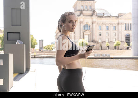 Junge Frau unter Bruch von Übung und Sie ihr Smartphone in der Stadt, Berlin, Deutschland Stockfoto