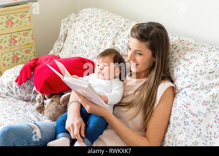 Mutter Baby girl auf Sofa lesen Stockfoto