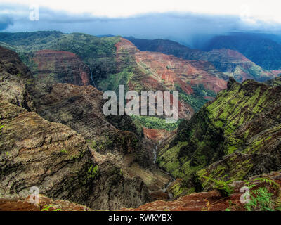 Spektakuläre Sicht auf den Waimea Canyon State Park an einem bewölkten Tag mit Wasserfall und Fluss, Kauai, Hawaii Stockfoto