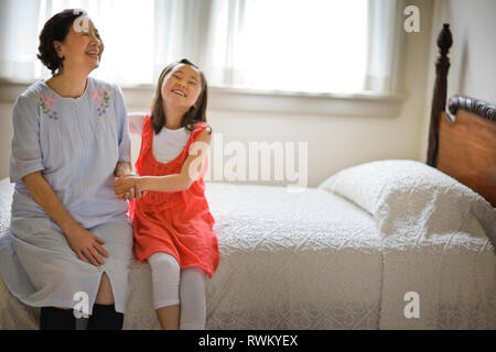 Eine Großmutter sitzt auf dem Bett mit ihrer Enkelin. Stockfoto