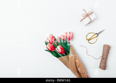 Blumenstrauß aus Schöne Tulpe Blumen neben Geschenk, Jute und gold Schere, Ansicht von oben. Flach Anordnung Konzept der Vorbereitung für die Ferien, zu kopieren. Stockfoto