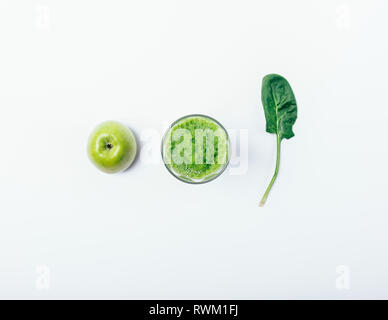 Kreative flach Zusammensetzung von Glas grüne Smoothie neben ganzen Apfel und Spinat Blatt auf weißem Hintergrund, Ansicht von oben. Konzept der gesunden Ernährung Stockfoto