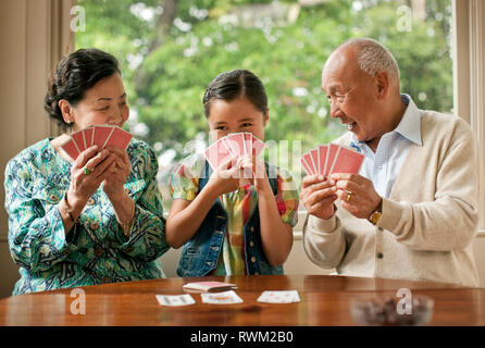 Junge Mädchen Spaß haben Spielen Kartenspiel mit ihren Großeltern. Stockfoto