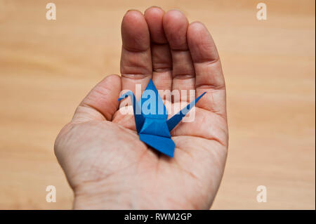 Männliche hand mit einem blauen origami Vogel Stockfoto