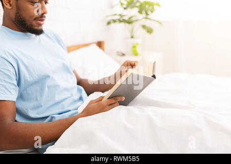 Schwarzer Mann Studium der Literatur im Bett Stockfoto