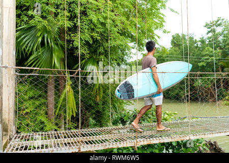 Mann mit Surfbrett auf der Seilbrücke, Pagudpud, Ilocos Norte, Philippinen Stockfoto