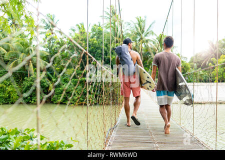 Männer mit Surfbrettern auf der Seilbrücke, Pagudpud, Ilocos Norte, Philippinen Stockfoto