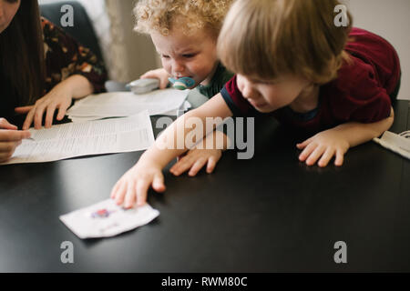 Mutter ausfüllen Formular mit Kinder spielen am Tisch Stockfoto