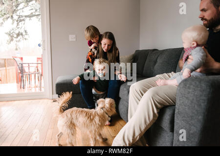 Familie und Kinder mit Hund im Wohnzimmer Stockfoto