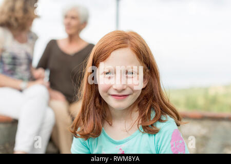 Rothaarige Mädchen mit Mutter und Großmutter im Hintergrund, Porträt Stockfoto