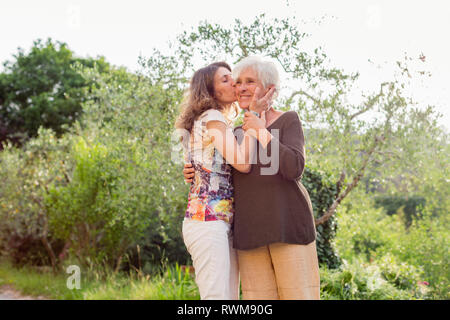 Reife Frau Mutter Küssen auf die Wange in Garten Stockfoto