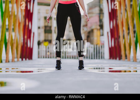 Von unten Erntegut junge Dame in Sportswear stehen auf der Straße bei schönem Wetter Stockfoto