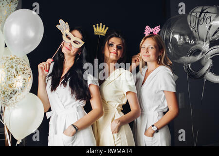 Brautjunfer tragen lustige Masken mit Braid posing Stockfoto