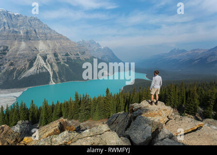 Ein Mann steht auf einem Rock Ridge mit Blick auf die atemberaubende türkise Wasser des Peyto Lake im Banff National Park, Alberta, Kanada Stockfoto