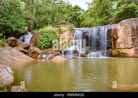 Wasserfall und See im Regenwald von Moeda in Minas Gerais state an bewölkten Tag unter Felsen und Vegetation Stockfoto