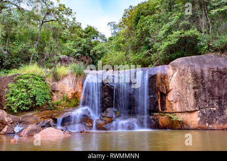 Wasserfall im Regenwald von Moeda in Minas Gerais state an bewölkten Tag unter Felsen und Vegetation Stockfoto