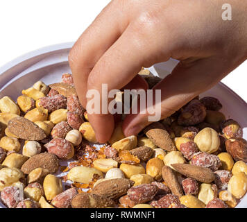 Hand, denn einige gemischte snacks Reiskräcker, Nüsse und getrocknete Fische über Kunststoff Teller auf weißem Hintergrund Stockfoto