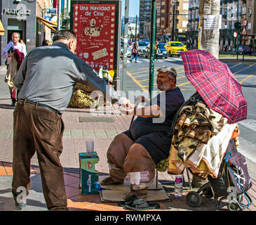 Murcia/Spanien - März 4 - 2019: Schlechte ungesunde Menschen betteln um Almosen in der Straße von Murcia, Spanien. Mann gibt Geld für die Armen. Stockfoto