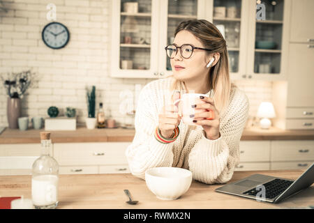 Friedliche gut aussehende Frau in klare Gläser holding Glas Tee Stockfoto