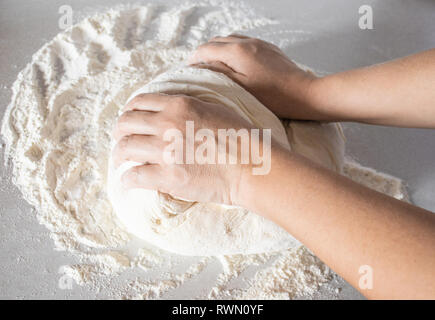 Mädchen knetet Teig auf einem weißen Tisch close-up. Stockfoto