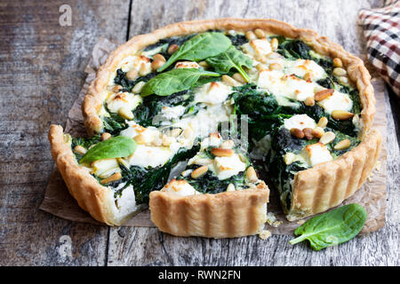 Vegetarische Spinat Tarte mit Feta und Pinienkernen auf hölzernen Tisch Stockfoto