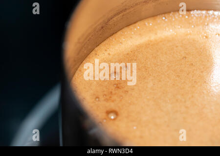 Kaffee in der Türke ist auf dem Herd gekocht. Nahaufnahme von oben Stockfoto