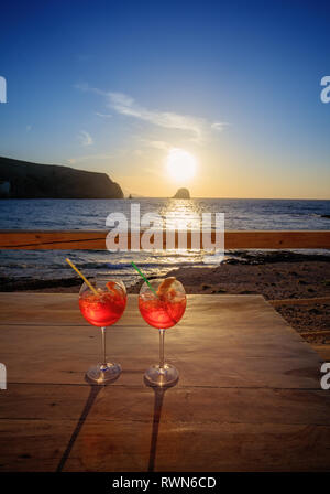 Aperol Spritz (Aperitif, Cocktail, bestehend aus Prosecco, Aperol und Sodawasser). Zwei Gläser auf den Tisch am Strand bei Sonnenuntergang Stockfoto