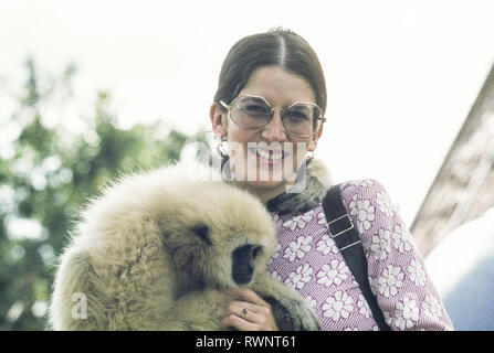 Attraktive junge Frau auf Tour in Thailand durchlöcherte einen Affen zu einem Streichelzoo, Bangkok, 1975 Stockfoto