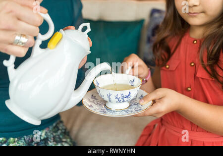 Eine Mutter gießen Kaffee in eine Tasse mit Untertasse für ihre Tochter, Surrey, British Columbia, Kanada Stockfoto