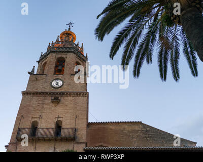 Kirchturm mit Uhr vor blauem Himmel und Palmen im Vordergrund; Ronda, Malaga, Spanien Stockfoto