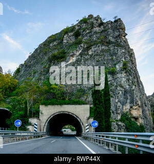 Eine Straße, die durch einen dunklen Tunnel mit Schildern die empfohlene Verwendung von Scheinwerfer; campillo de Arenas, Provinz Jaen, Spanien Stockfoto