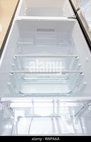 Neuer Kühlschrank öffnen. Leeren Kühlschrank mit offener Tür, Ansicht von unten. Stockfoto