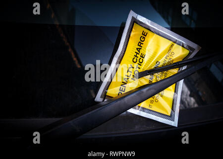 Gelbe Frontscheibe Aufkleber mit einem festen Strafe Parken kostenlos Hinweis für illegales Parken feine Gebühr klemmt auf ein Auto Windschutzscheibe. Stockfoto