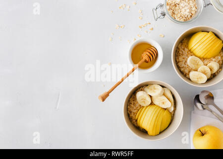 Gesundes Frühstück Ansicht von oben. Haferflocken mit Obst (Äpfel, Bananen) und Honig. Im rustikalen Stil Stockfoto