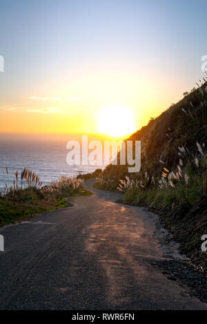 Big Sur, Kalifornien - kurvenreiche Straße führt Sie die küstennahen Hügeln auf den Pazifischen Ozean und den Sonnenuntergang. Stockfoto