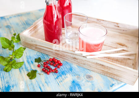 Erfrischende Sommer Obst-Drink von roten Johannisbeeren. Berry Getränke auf weißen und blauen Holz Hintergrund Stockfoto