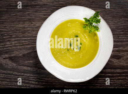 Grüne Erbsensuppe in einer weißen Schüssel auf einem dunklen Hintergrund. Stockfoto