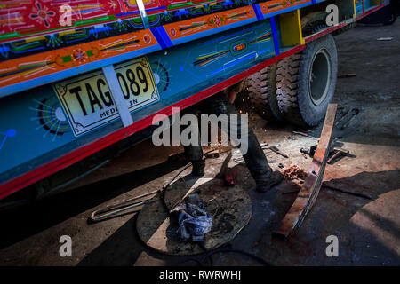 Eine kolumbianische Automechaniker arbeitet auf Suspension System eines Fahrzeugs in einer Autowerkstatt im Barrio Triste, Medellín, Kolumbien. Stockfoto