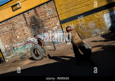 Kolumbianische rad Mechaniker roll Reifen auf der Straße von Barrio Triste, einem Automechaniker Nachbarschaft in Medellín, Kolumbien. Stockfoto