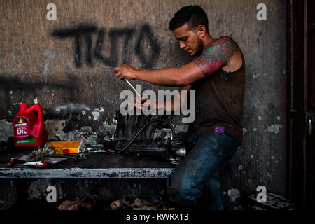 Eine kolumbianische Automechaniker arbeitet auf einem Motor in einer Autowerkstatt im Barrio Triste, Medellín, Kolumbien. Stockfoto