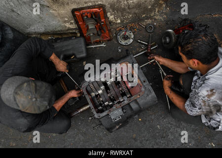 Kolumbianische Automechaniker arbeiten an einem Getriebe in eine Autowerkstatt im Barrio Triste, Medellín, Kolumbien. Stockfoto