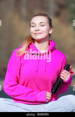 Fitness junge Frau sport Jugendmädchen mit engen Augen in Pink tracksuit Holding tablet Touchpad Computer erhalten die Sonne auf ihr Gesicht outdoor. Feder Stockfoto