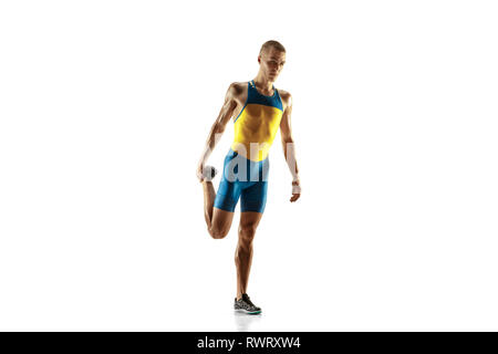 Jungen kaukasischen Mann Aufwärmen vor dem Laufen auf weiße studio Hintergrund isoliert. Eine männliche Läufer oder Jogger. Silhouette von Stretching Athlet mit Schatten. Stockfoto