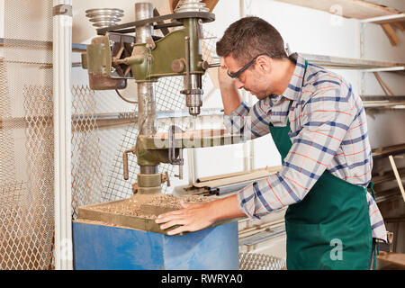 Der Mensch als Schreiner arbeitet auf eine Bohrmaschine in der Schreinerei Stockfoto