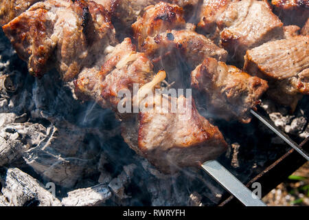 Gegrilltes kebab Kochen auf Metall Spieß. Schaschlik aus Würfeln von Fleisch auf die Spieße während des Kochens auf der mangal über Holzkohle im Freien. Grill auf Stockfoto