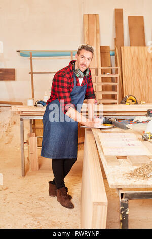 Schreiner oder Tischler in seinem Workshop mit Zwischenablage auf der Werkbank Stockfoto