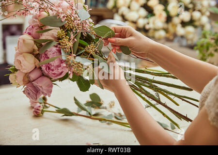 Florist Blumenstrauß aus Rosen und Pfingstrosen am Arbeitsplatz Stockfoto
