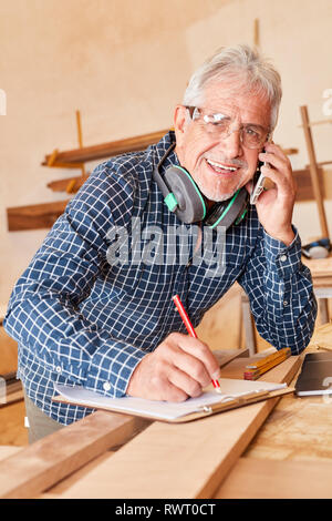 Senior Handwerker mit Handy Hinweise Termine und Zwischenablage Termine Stockfoto