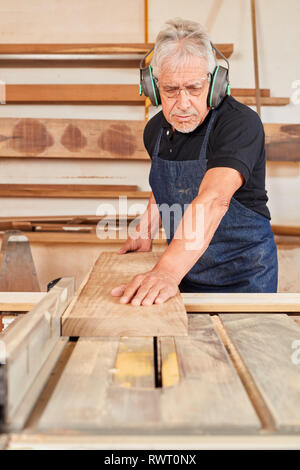 Ältere Menschen als Schreiner arbeitet mit Holz auf der Kreissäge in der Schreinerei Stockfoto