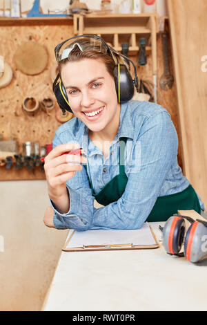 Lächelnden jungen Frau als Handwerker Lehrling mit Checkliste in der Werkstatt Stockfoto